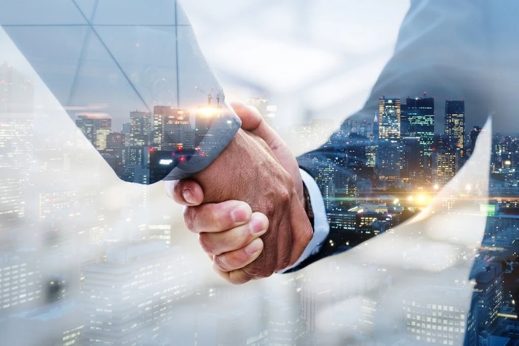 Two business partners shaking hands over a city skyline